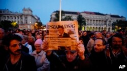 FILE - A man holds up the last printed edition of Nepszabadsag during a demonstration organized to express solidarity with the Hungarian political daily Nepszabadsag in Budapest, Hungary, Oct. 8, 2016. 