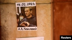 Fotografija ruskog opozicionog lidera Alekseja Navalnog stoji na zidu dok ljudi prisustvuju bdijenju nakon njegove smrti, Pariz, 19. februar 2024.