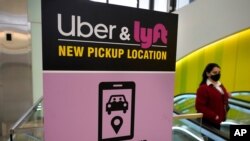 Seorang pejalan kaki melintas di depan papan layanan transportasi daring Uber dan Lyft di Bandara Internasional Logan, di Boston, Massachusetts, 9 Februari 2021.