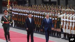 In this Aug. 31, 2015 file photo, Chinese President Xi Jinping, center, accompanies Kazakhstan President Nursultan Nazarbayev, right, to view an honor guard during a welcoming ceremony outside the Great Hall of the People, in Beijing. 