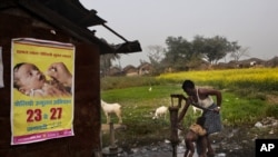 Seorang Bapak memandikan anaknya dengan air dari pompa, di samping peringatan mengenai penyakit polio di Kosi, Mathura, negara bagian Uttar Pradesh. India (foto: dok).