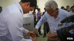 រូបឯកសារ៖ មន្ត្រី​ការិយាល័យ​បោះឆ្នោត​កាន់​ដៃ​ក្រុម​ប្រឹក្សា​​សង្កាត់​មួយរូប​ជ្រលក់​ទឹក​ថ្នាំ​ បន្ទាប់​ពី​បាន​បោះ​ឆ្នោត​ព្រឹទ្ធ​សភា ​នៅ​ភ្នំពេញ ​កាល​ពី​ថ្ងៃទី២៥ ​ខែកុម្ភៈ ​ឆ្នាំ២០១៨។ ​(អូន ឆេងប៉រ/VOA) 