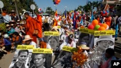 សកម្មជន​ដីធ្លី​កម្ពុជា​បង្ហាញ​រូបថត​របស់​សហការី​របស់​ពួកគេ​ដែល​ត្រូវបាន​ឃុំខ្លួន​ ក្នុង​កំឡុង​ពេល​ប្រមូលផ្តុំគ្នា​ដើម្បី​ប្រារព្ធ​ទិវាសិទ្ធិមនុស្សអន្តរជាតិ​ នៅ​ពីមុខវិមាន​រដ្ឋសភាជាតិ​ ក្នុង​ទីក្រុង​ភ្នំពេញ​ កាលពី​ថ្ងៃពុធ​ ទី១០ ​ខែធ្នូ ​ឆ្នាំ២០១៤។ (​រូបថត​ដោយ: AP/Heng Sinith)