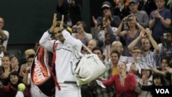 Petenis Swiss Roger Federer melambai kepada penonton setelah memenangkan pertandingan putaran kedua melawan petenis Perancis Adrian Mannarino di Wimbledon, Kamis (23/6).
