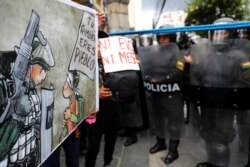 Protestors hold a sign as riot police stand guard during a march in La Paz, Bolivia, Oct. 25, 2019. The sign reads: "You too are the people."