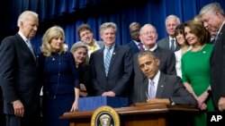 Presiden AS Barack Obama menandatangani UU Penyembuhan Abad 21 di auditorium Gedung Putih, Washington (13/12), disaksikan Wakil Presiden Joe Biden (kiri) dan para anggota Kongres. (AP/Pablo Martinez Monsivais)