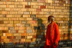 FILE - A Sadhu (Hindu holy man) looks at bricks for the proposed Hindu temple in Ayodhya, India, after the Supreme Court verdict on the disputed religious site, Nov. 12, 2019.