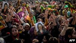 FILE - Kurds celebrating success by Kurd and peshmerga fighters to drive Islamic State militants out of Kobani hold a photo of a fighter killed in the conflict, near the Turkish-Syrian border at Suruc, in Sanliurfa province, Jan. 27, 2015.