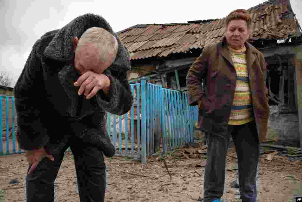 Valentina Fedoryak and her husband stand outside their home damaged by shelling in Donetsk, Eastern Ukraine, Wednesday, Nov. 12, 2014.