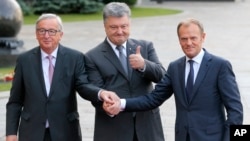 Ukrainian President, Petro Poroshenko, center, European Council President Donald Tusk, right, and European Commission President Jean-Claude Juncker shakes hands during a meeting in Kiev, Ukraine, July 13, 2017. 