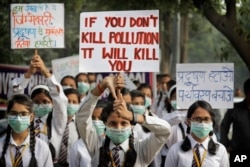 FILE - Schoolchildren hold banners to express their distress at the alarming levels of pollution in the city, in New Delhi, India, Nov. 15, 2017.
