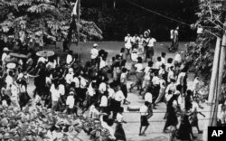 FILE - Despite martial law, Buddhist monks and students carry a flag in protest against the government, Aug. 9, 1988, in downtown Rangoon.