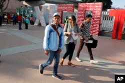 FILE - Two men, both of Honduras, walk with attorneys as they cross into the United States to begin their asylum cases, March 19, 2019, in Tijuana, Mexico.