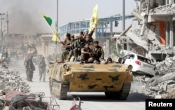 Syrian Democratic Forces (SDF) fighters ride atop of military vehicle as they celebrate victory in Raqqa, Syria, October 17, 2017. REUTERS/Erik De Castro