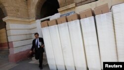 A man walks past rows of election ballot boxes, before they are transported to polling offices, in the premises of the district city court in Karachi May 8, 2013.