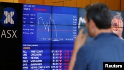 Seorang pria mengamati papan yang menampilkan harga-harga saham di Bursa Saham Australia (ASX) di Sydney, Australia (9/11). 