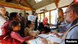 Photo: Des réfugiés de l’Irak et de la Syrie et de l'Irak parlent avec des médecins avant un contrôle médical après leur arrivée au centre Hubert Renaud à Cergy-Pontoise, près de Paris, France, le 9 septembre 2015. REUTERS/Jacky NaegelenATTENTION EDITORS : FRENCH LAW REQUIRES THAT THE FACES OF MINORS ARE MASKED IN PUBLICATIONS - RTSB2V