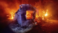 FILE - In this Aug. 19, 2020, file photo, flames from the LNU Lightning Complex fires consume a home in unincorporated Napa County, California.