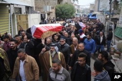 Mourners carry the Iraqi-flag-draped coffins of bomb victims Arif Muhanad, 36, and his son, Muhanad, 8, during their funeral procession in Baghdad, Iraq, Dec 31, 2016. A pair of bomb blasts targeting a market Saturday in central Baghdad killed and wounded many people, officials said.