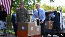 美国副总统迈克·彭斯(Mike Pence)在弗吉尼亚州亚历山大市的伍德宾康复和医疗中心(Woodbine Recovery And Healthcare Center)移动一辆手推车，车里装着来自联邦应急管理局(FEMA)的一箱箱个人防护用品。（2020年5月7日）