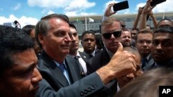 FILE - Brazil's President Jair Bolsonaro flashes a thumbs up as he greets supporters after attending a Changing of the Guard at the Planalto Presidential Palace, in Brasilia, Brazil, Thursday, Nov. 28, 2019