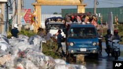 រូបឯកសារ៖ ​រថយន្ត​ដឹក​កម្មករ​​តាម​ផ្លូវ​មួយ​ដែល​ត្រូវ​លិច​ទឹក​និង​មាន​​​​គំនរ​សំរាម​នៅ​ជាយ​ក្រុង​ភ្នំពេញ​កាល​​ពី​​ខែ​តុលា ឆ្នាំ​២០១៨។
