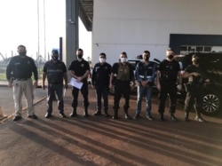 Personnel of the General Directorate of Migration, agents of the Paraguayan office of INTERPOL and members of the Federal Police of Brazil pose for a photo, during the handover of Brazilian citizen Chelbe Willams Moraes in an unknown location, June 7, 2021.