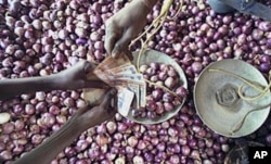 An Indian vendor receives money from a customer as he sells onions in Bhubaneswar.