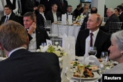 FILE - Russian President Vladimir Putin (R) sits next to retired U.S. Army Lieutenant General Michael Flynn (L) as they attend an exhibition marking the 10th anniversary of RT (Russia Today) television news channel in Moscow, Russia, Dec.10, 2015.