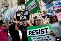 Protesters hold up signs and chant slogans outside a cybersecurity summit, July 31, 2018, in New York.