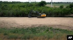 Construction equipment sets in an area of demolished trees and brush, April 29, 2019, where construction is set to begin soon, in Mission, Texas.