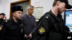 Founder of the Baring Vostok investment fund Michael Calvey, center, is escorted to the courtroom in Moscow, Feb. 15, 2019. A veteran U.S. investment fund manager has been detained in Moscow and faces fraud charges.