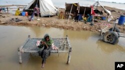 FILE - A woman, surrounded by floodwaters, sits near her belongings, in Sohbat Pur, Pakistan, Sep. 3, 2022. The flooding that year killed at least 1,700 people. The nation's weather officials reported on May 3, 2024, that Pakistan last month had its wettest April since 1961.