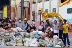 Para pengunjuk rasa berdiri di belakang barikade di distrik Sanchaung, Yangon, Myanmar, 8 Maret 2021.