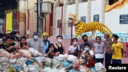Protesters stand behind a barricade at Sanchaung district in Yangon, Myanmar, March 8, 2021. 