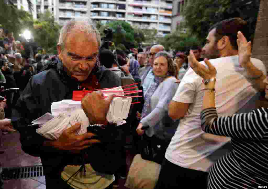A man holds ballots at a polling station for the banned independence referendum in Barcelona, Oct. 1, 2017.