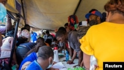 아이티 수도 포르토프랭스로 송환된 미국 이주 희망자들이 현지 텐트에서 당국에 등록 절차를 밟고 있다. 