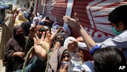 FILE - Women wait to receive free food for the Muslim fasting month of Ramadan, during a government-imposed nationwide lockdown to help contain the spread of the new coronavirus, in Peshawar, Pakistan, May 5, 2020. 