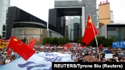 ពលរដ្ឋហុងកុងដែលគាំទ្ររដ្ឋាភិបាលហុងកុងបាននាំគ្នាកាន់ទង់ជាតិចិន នៅក្នុងការដើរហែរក្បួនមួយដោយបង្ហាញការគាំទ្រប៉ូលិស និងទាមទារឲ្យបញ្ចប់អំពើហិង្សានៅក្រុងហុងកុង ថ្ងៃទី១៧ ខែសីហា ឆ្នាំ២០១៩។ (REUTERS/Thomas Peter)