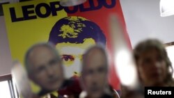 Orang-orang mengangkat foto pemimpin oposisi Antonio Ledezma di depan sebuah dinding dengan foto pemimpin oposisi Leopoldo Lopez dalam sebuah konferensi pers di markas besar partai oposisi koalisi Venezuela di Caracas, Venezuela (foto: REUTERS/Ueslei Marcelino)