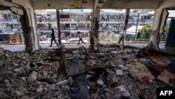Anak-anak berjalan melewati ruang kelas yang hancur tempat orang-orang berlindung di sebuah sekolah yang dikelola oleh Badan Bantuan dan Pekerjaan PBB untuk Pengungsi Palestina (UNRWA) yang sebelumnya terkena pengeboman Israel, di kamp Nuseirat di Jalur Gaza tengah. (Foto: AFP)