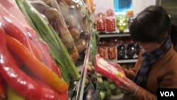 A shopper reads packaging on vegetables on sale at Veggies, a grocery shop in central Hanoi listed on a website providing consumers with information on where to buy "safe" vegetables, March 28, 2014. (Marianne Brown/VOA)