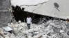 A resident walks upon the debris of buildings which were damaged in what activists say was one of Tuesday's U.S. airstrikes in Kfredrian, Idlib province, Sept. 24, 2014. 