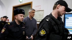 Founder of the Baring Vostok investment fund Michael Calvey, center, is escorted to the courtroom in Moscow, Feb. 15, 2019. A veteran U.S. investment fund manager has been detained in Moscow and faces fraud charges.