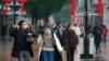 Masked pedestrians walk down a shopping street in downtown Wuhan, China, Jan. 22, 2020. 
