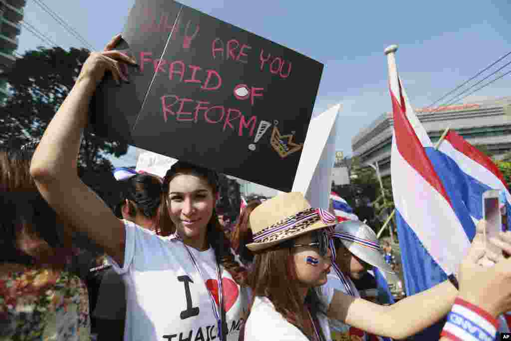 A Thai anti-government protester holds a banner as she joins a rally outside Prime Minister Yingluck Shinawatra&#39;s residence, Dec. 22, 2013, Bangkok, Thailand.