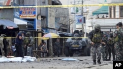 Police investigators and soldiers attend the scene after two bombs exploded outside a Roman Catholic cathedral in Jolo, the capital of Sulu province in southern Philippines, Jan. 27, 2019. 