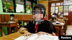 Siswa sekolah dasar yang memakai masker dan pelindung wajah mengikuti kelas, saat sekolah dibuka kembali di tengah pandemi COVID-19, di Jakarta, 7 April 2021. (Foto: REUTERS/Ajeng Dinar Ulfiana)