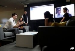 Canada's Prime Minister Justin Trudeau, left, speaks with AppDirect employees at their office in San Francisco, Feb. 8, 2018.