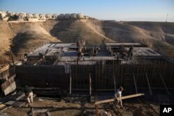 FILE - Palestinian laborers work at a construction site in a new housing project in the Israeli settlement of Maale Adumim, near Jerusalem, Feb. 7, 2017. Yaakov Katz, a prominent West Bank settler, says the rapid growth in the number of Israelis settling in the West Bank means the internationally backed idea of a two-state solution between Israel and the Palestinians is now impossible.